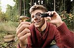 Teenage boy looking at mushroom through magnifying glass, Bavaria, Germany, Europe