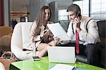 Businessman and businesswoman at meeting with laptop and tablet