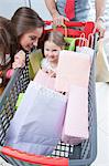 Close-up of young daughter in trolley being pushed by father and mother