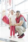 Father kneels with younger daughter holding balloon