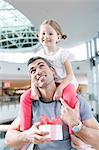 Young daughter sits on fathers shoulders