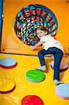 Young girl climbing up ramp into tunnel at soft play centre