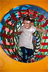 Young girl climbs through netted tunnel in soft play centre