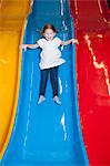 Young girl slides down colorful slide