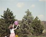 Young girl catching purple ball in park