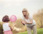 Mother throwing ball to daughter in park