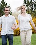 Close-up of Couple running through park holding hands