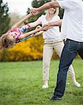 Young couple swinging daughter between them