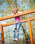 Young girl standing at top of rope and climbing frame