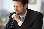 Businessman looking away in thought, glasses in hand