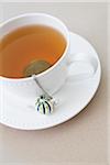 cup of tea with tea infuser and loose tea leaves on saucer