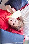 Boy on bed playing with paper aeroplane