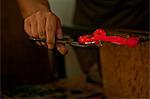 Person holding red hot glass in glass factory