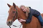 Woman riding horse on beach