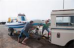 Two young men fixing dinghy trailer to vehicle