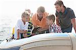 Small group of young men and young boys sea fishing in dinghy