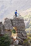 Young man standing on rock formation with mountain bike