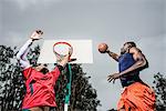 Young basketball players jumping to score hoop