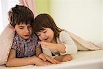 Brother and sister playing game in bed