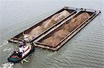 Tugboat pushing barges of sand, high angle view