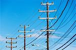 Cables attached to telegraph pole against blue sky