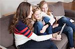 Girls sitting on sofa using digital tablet