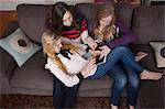 Girls sitting on sofa using digital tablet