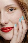 Cropped shot of young woman with curly red hair wearing make up, hand on chin