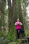 Mature woman performing tree pose in forest