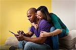 Mid adult couple sitting on sofa looking at digital tablet