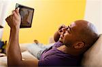 Mid adult male on sofa holding digital tablet and mobile phone