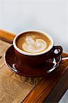 Latte with a Floral Design on a Newspaper Topped Table