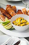 Grilled Salmon with Mango Salsa and Lime Wedges on a Platter on a Table