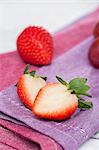 Whole and halved strawberries lying on a napkin