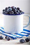 Lots of blueberries in an enamel mug