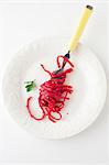 Whole Wheat Linguine with Roasted Beat Puree and Chia Seeds Twirled Around a Fork on a White Plate