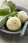 Two kohlrabi in a bowl with a knife