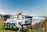 A table laid in the country house style, on an alpine meadow with a view over the Alps