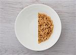 A halved portion of cereal in a white bowl (view from above)