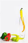 Assorted peppers, one in a glass vase