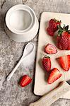 Strawberries on a chopping board; scattered sugar to one side