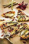 Sliced Asparagus and Sun Dried Tomato Pizza with a Pizza Cutter
