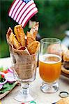 Potato wedges on a table outside, in the background buffalo burgers and a US flag