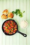 Spicy turkey goulash in the pan with rice and bread rolls