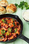 Spicy turkey goulash in a pan, with rice and bread rolls