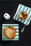 A hamburger with lettuce, tomato and gherkin, served with rosemary potatoes