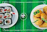 Sushi (Japan) and salgadinhos (Brazil) with football-themed decoration