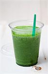 A green smoothie made with spinach, lamb's lettuce, apple, banana and apple mint in a plastic cup