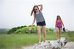 Young women walking along log on beach