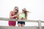 Young women using mobile phones on pier